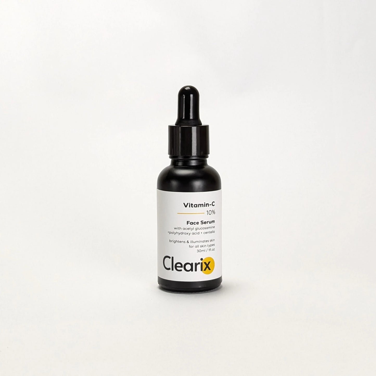 Clearix Vitamin-C 10% Face Serum in a black dropper bottle displayed against white background. Image featured with black dropper bottle and white label and yellow and black writting on it. Formulated with acetyl glucosamine, polyhydroxy acid, and centella. Serum brightens and illuminates the skin. Suitable for all skin types.